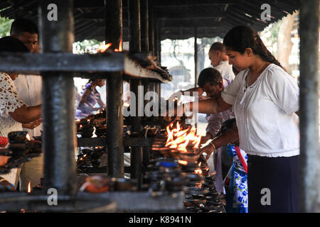 Kandy, Sri Lanka - Januar 4, 2017: Menschen Beleuchtung Kerzen für Gebete außerhalb der Tempel des Zahns im Stadtzentrum von Kandy, Sri Lanka Stockfoto