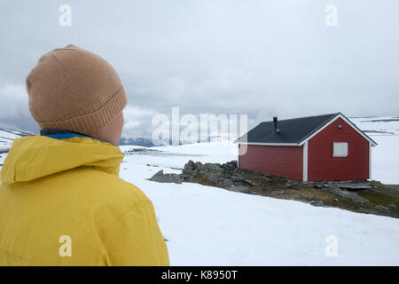 Der Mensch in der Nähe von typischen norwegischen roten Holzhaus in der Nähe von Aurlandsvegen (Bjorgavegen) Mountain Road, Aurland, Norwegen im Sommer Stockfoto