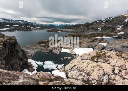 Typisch norwegische Landschaft mit schneebedeckten Bergen und Clear Lake in der Nähe der berühmten Aurlandsvegen (Bjorgavegen), Mountain Road, Aurland, Norwegen. Stockfoto