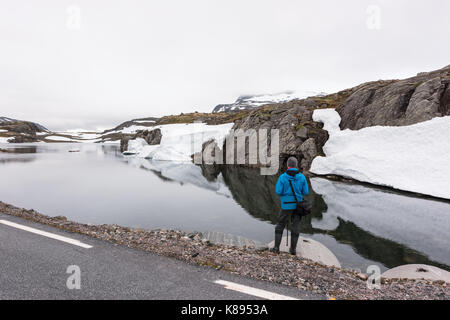 Fotograf, Foto, typisch norwegische Landschaft mit schneebedeckten Bergen und Clear Lake in der Nähe der berühmten Aurlandsvegen Mountain Road, Aurland, noch Stockfoto