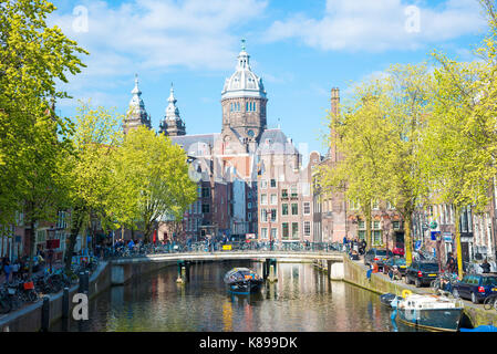 Amsterdam, Niederlande - 19. April 2017: Kanal mit Booten und St. Nicolas Kirche in Amsterdam, Niederlande Stockfoto