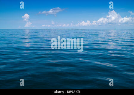 Dauphin Insel am Horizont in der Ferne sitzt unter einer Bank für das Ansammeln von Gewitterwolken. Stockfoto