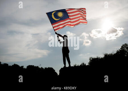 Die Silhouette eines jungen Holding die malaysische Flagge Malaysia feiert den Tag der Unabhängigkeit Stockfoto