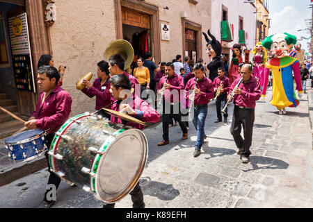 Eine Blaskapelle führt eine Prozession von riesigen Pappmaché-Puppen namens Mojigangas im Jardin Allende während einer Kinderparade, die den mexikanischen Unabhängigkeitstag feiert 17. September 2017 in San Miguel de Allende, Mexiko. Stockfoto