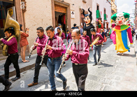 Eine Blaskapelle führt eine Prozession von riesigen Pappmaché-Puppen namens Mojigangas im Jardin Allende während einer Kinderparade, die den mexikanischen Unabhängigkeitstag feiert 17. September 2017 in San Miguel de Allende, Mexiko. Stockfoto