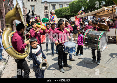 Eine Blaskapelle führt eine Prozession von riesigen Pappmaché-Puppen namens Mojigangas während einer Kinderparade anlässlich der Feierlichkeiten zum mexikanischen Unabhängigkeitstag am 17. September 2017 in San Miguel de Allende, Mexiko. Stockfoto