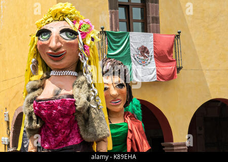 Riesige Pappmaché-Puppen namens Mojigangas tanzen im Jardin Allende während einer Kinderparade, die die Feierlichkeiten zum mexikanischen Unabhängigkeitstag am 17. September 2017 in San Miguel de Allende, Mexiko, feiert. Stockfoto