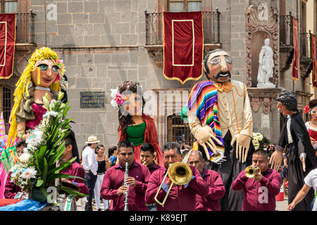 Eine Blaskapelle führt eine Prozession von riesigen Pappmaché-Puppen namens Mojigangas im Jardin Allende während einer Kinderparade, die den mexikanischen Unabhängigkeitstag feiert 17. September 2017 in San Miguel de Allende, Mexiko. Stockfoto