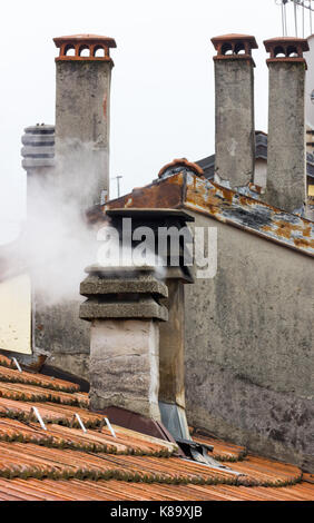 Schornstein mit Rauch kommt im italienischen Dach Stockfoto