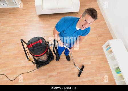 Hohe Betrachtungswinkel der männlichen Hausmeister Reinigung Boden mit Staubsauger Stockfoto