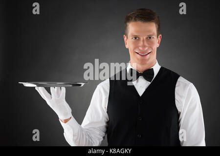 Junger Kellner Holding Silber Tablett in den Händen Stockfoto