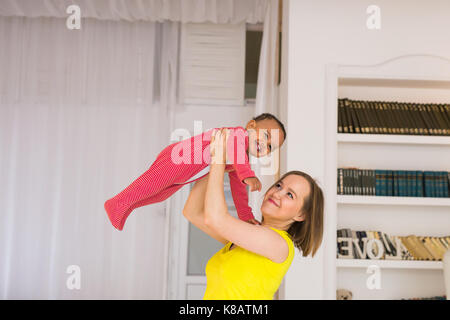 Glückliche Familie. Mutter wirft durcheinander Rennen Baby, zu Hause spielen Stockfoto