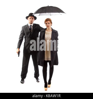 Eine nette Dame von einem Mann im Anzug mit einem Gewehr und einem Regenschirm begleitet Stockfoto
