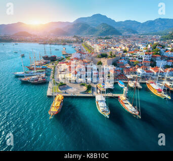 Luftaufnahme der Boote und der schönen Architektur bei Sonnenuntergang in Marmaris, Türkei. Bunte Landschaft mit Yachten in der Marina Bay, Meer, Stadt, in den Bergen. Top Stockfoto