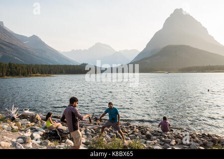 Junge Männer genießen Sie am späten Nachmittag die Kante/Ufer des Swiftcurrent Lake im Glacier National Park Stockfoto