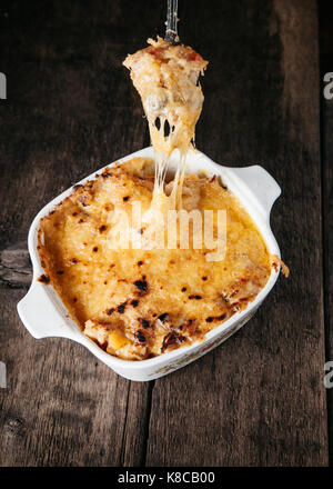 Cremige gebackenes Huhn Kasserolle mit shreded Cheddar Käse auf Holz- Oberfläche geschichtet Stockfoto