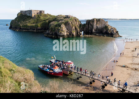 Touristen steigen Sie vom Boot am Steg am Strand von Tenby folgende Reise nach Insel Caldey/Ynys Bŷr mit St Catherine's Island im Hintergrund Stockfoto