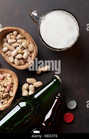 Lagerbier und Snacks auf Tisch aus Stein. Verschiedene Nüsse. Ansicht von oben Stockfoto