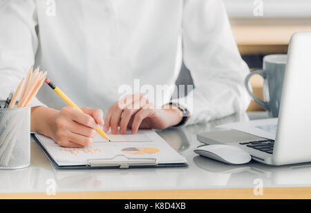 Nahaufnahme der Hand des Geschäftsfrau hand Schreiben einen Bericht vor Laptop auf Büro Schreibtisch, Office Lifestyle Stockfoto