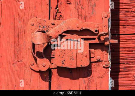 Alte Verriegelung in roter Farbe auf ein scheunentor abgedeckt. Stockfoto