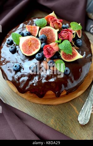 Сhocolate Kuchen mit Feigen, Beeren, Nüsse, Minze und Rosen dekoriert Stockfoto