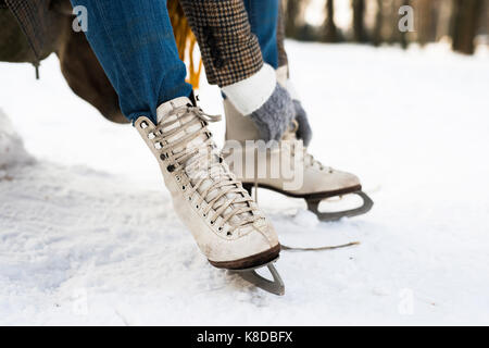 Nicht erkennbare Frau in Winterkleidung alte Schlittschuhe anziehen Stockfoto