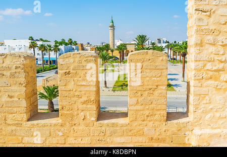 Der Blick durch die mittelalterlichen Festungsmauern der Ribat Festung auf dem palm Gasse und das Minarett von Habib Borguiba Moschee, Monastir, Tunesien. Stockfoto