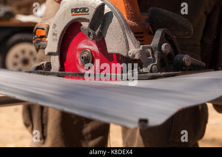 Ein Bauarbeiter mit einem Handheld Kreissäge durch Vinylabstellgleis in Ontario, Kanada zu schneiden. Stockfoto