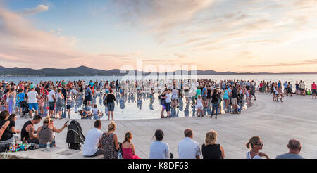 Menschen bei Sonnenuntergang am Meer auf kreisförmigen solar panel installation Gruß an die Sonne vom Architekten Nicola Basic in Zadar, Kroatien. Stockfoto