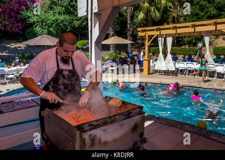 Hispanic Mann, Koch, Kochen auf Flat Top Grill, Grillen, Fleisch, grillen, Fleisch, Bratpfanne, Poolparty, Castro Valley, Alameda County, Kalifornien Stockfoto