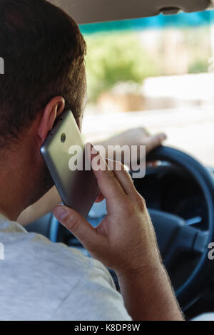 Mann auf dem Handy während der Fahrt ein Auto. Stockfoto