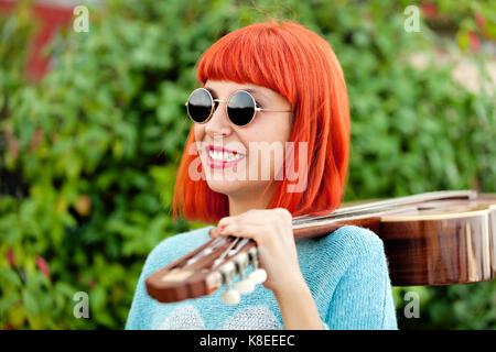 Rothaarige Frau mit einer Gitarre in einem Park mit der Musik genießen. Stockfoto