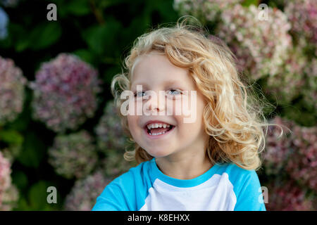 Süßes kleines Kind mit langen Haaren im Garten Stockfoto