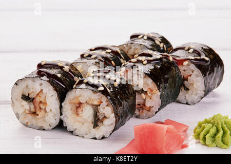 Japanische Küche - Sushi und Brötchen mit Fisch und Meeresfrüchten, Gemüse, Frischkäse auf weißem Holz Hintergrund. Brötchen, Ingwer, Wasabi, Stäbchen Stockfoto