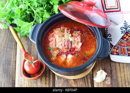 Fasten essen. Gemüsesuppe mit Sauerkraut, rote Beete, Karotten, Zwiebeln, Tomaten in einen schwarzen Topf auf einem hölzernen Hintergrund. Traditionelle Osteuropäische Stockfoto