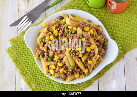 Pasta mit Hackfleisch, Erbsen und gelben Mais in einem weißen Teller. Hausmannskost. Gesunde Ernährung-Konzept Stockfoto