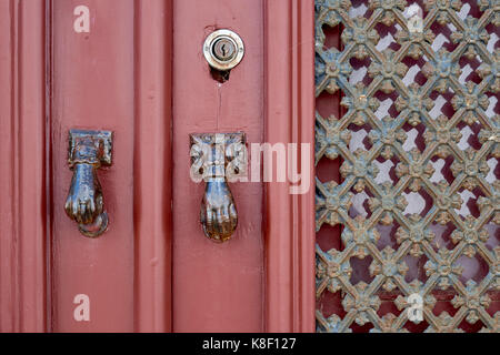 Detail einer roten Tür mit Türklopfer in der Form der Hand der Fatima, in dem Dorf Estoi, Algarve, Portugal. Stockfoto