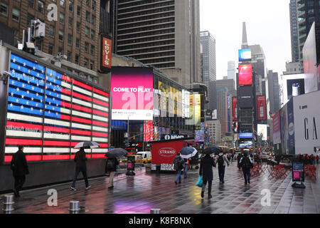NEW YORK, USA - MÄRZ 2017 - Blick auf Times Square an einem regnerischen Tag, die amerikanische Flagge ist an der Seite auf ein elektronisches Bedienfeld angezeigt Stockfoto