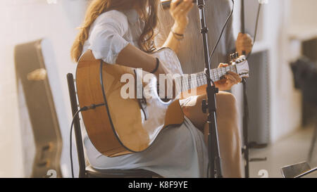 Frau mit Gitarre auf der Bühne auf dem Dachboden Stockfoto