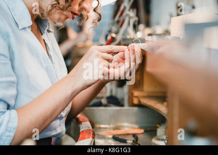 7/8 shot der weiblichen Juwelier Gestaltung silber Metall an Workbench Stockfoto