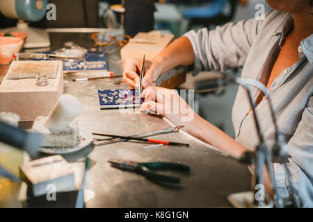 Weibliche Juwelier Abholung silber Metall mit einer Pinzette in der Workbench Stockfoto