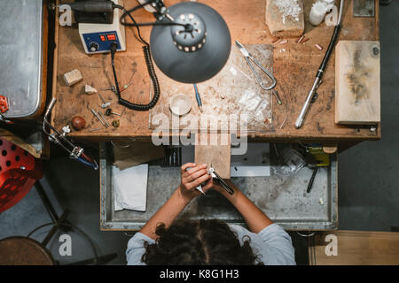 Ansicht der weiblichen Juwelier mit der Bewältigung sah in der Workbench Stockfoto