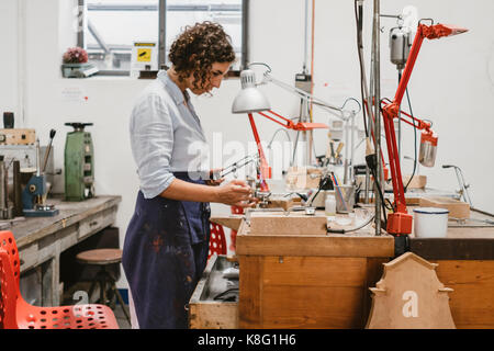 Weibliche Juwelier mit Brenner an der Werkbank Stockfoto