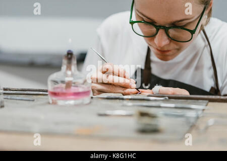 Weibliche Juwelier arbeiten mit Miniatur Werkzeug Hand in Workbench Stockfoto