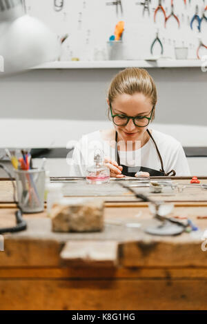 Weibliche Juwelier arbeiten mit Miniatur Werkzeug Hand in Workbench Stockfoto