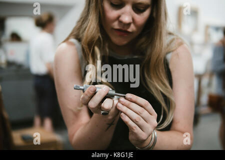 Weibliche Juwelier mit Werkzeug Hand in Schmuck workshop Stockfoto