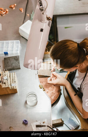 Hohe Betrachtungswinkel der weiblichen Juwelier mit Werkzeug Hand in Workbench Stockfoto