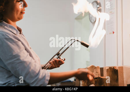 Weibliche Juwelier mit flammenden Brenner an der Werkbank Stockfoto