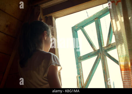Junges Mädchen aus lichtdurchfluteten Schlafzimmer Fenster Stockfoto