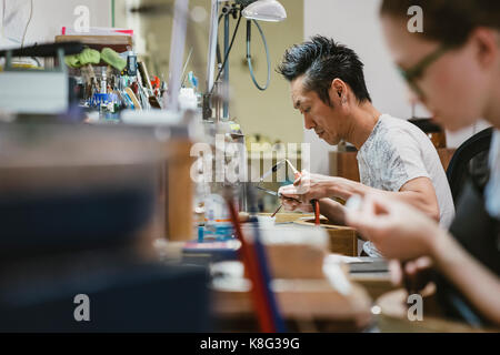 Männliche Juwelier mit Brenner an der Werkbank Stockfoto